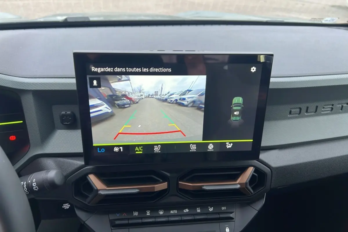 Vue intérieure du tableau de bord du Dacia Duster 2025 avec écran tactile affichant la caméra de recul et aérateurs hexagonaux.