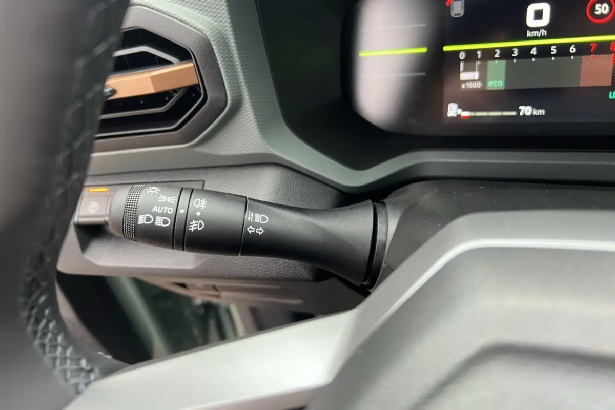 Gros plan sur la commande des phares à gauche du volant dans le tableau de bord du Dacia Duster 2025 kaki lichen.