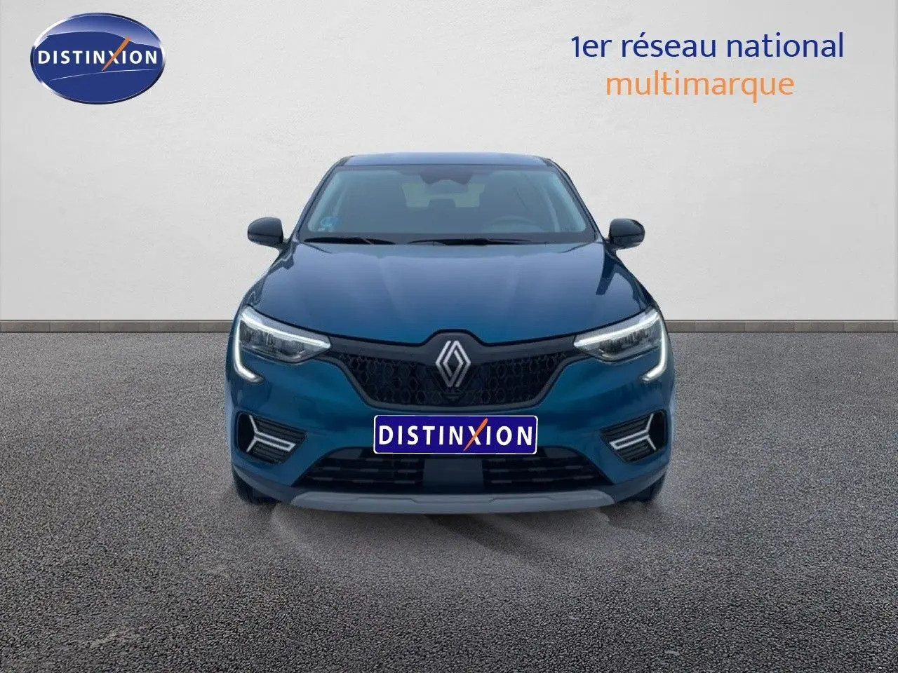 Vue frontale d'une Renault Arkana bleu Zanzibar métal avec calandre noire et feux LED allumés sur fond neutre.