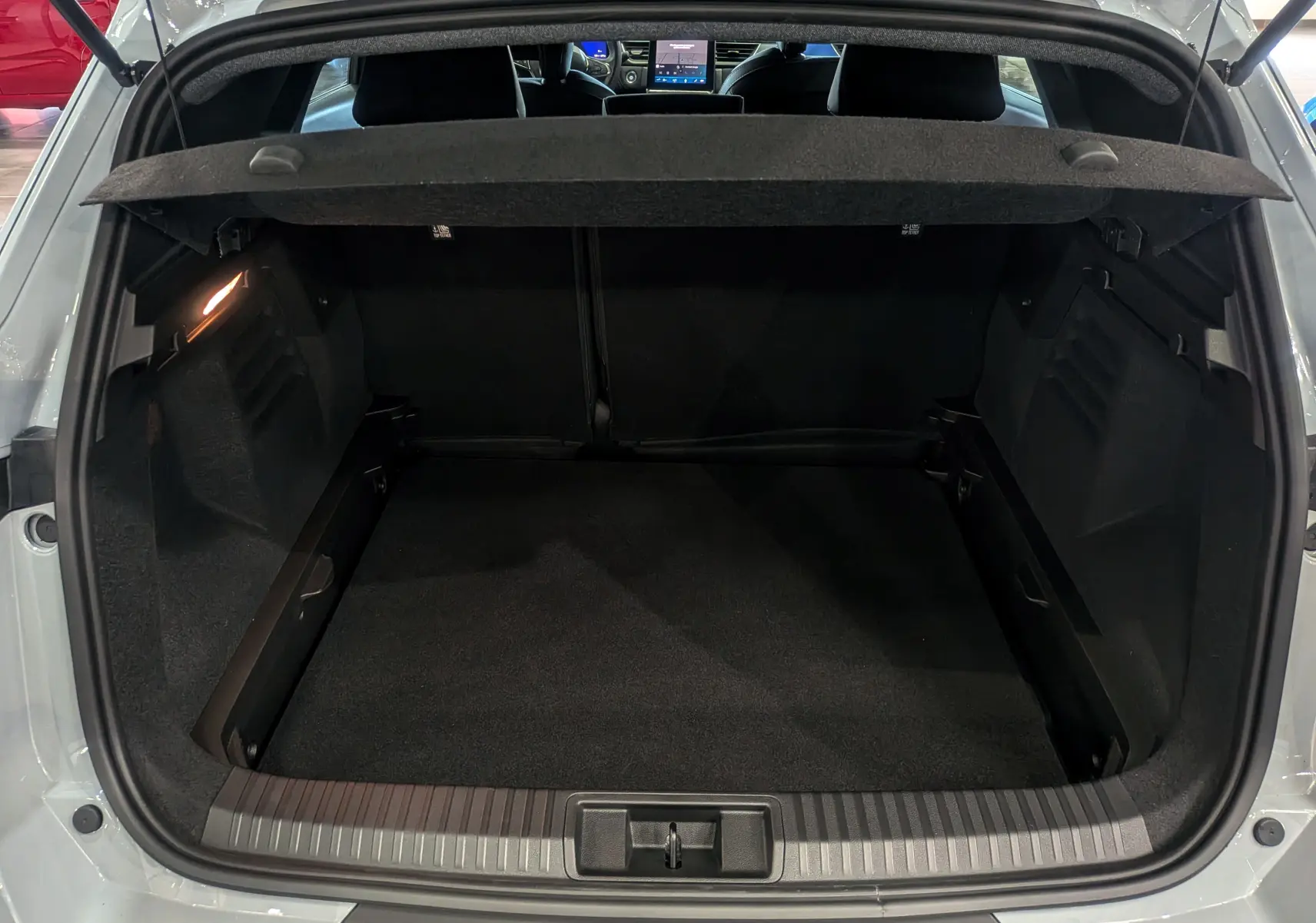 Coffre ouvert vu de l'arrière d'une Renault SYMBIOZ gris Rafale, montrant l'espace de chargement et la tablette cache-bagages.