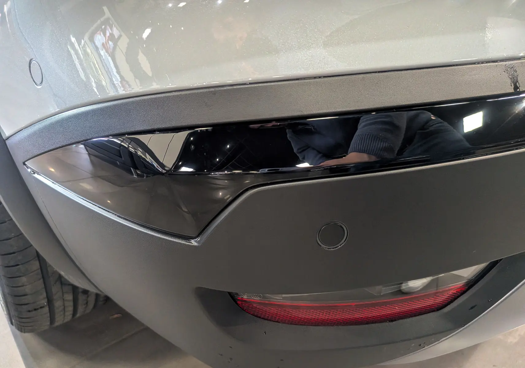 Gros plan sur le pare-chocs arrière gris Rafale de la Renault Symbioz avec un insert noir brillant et un feu rouge inférieur.