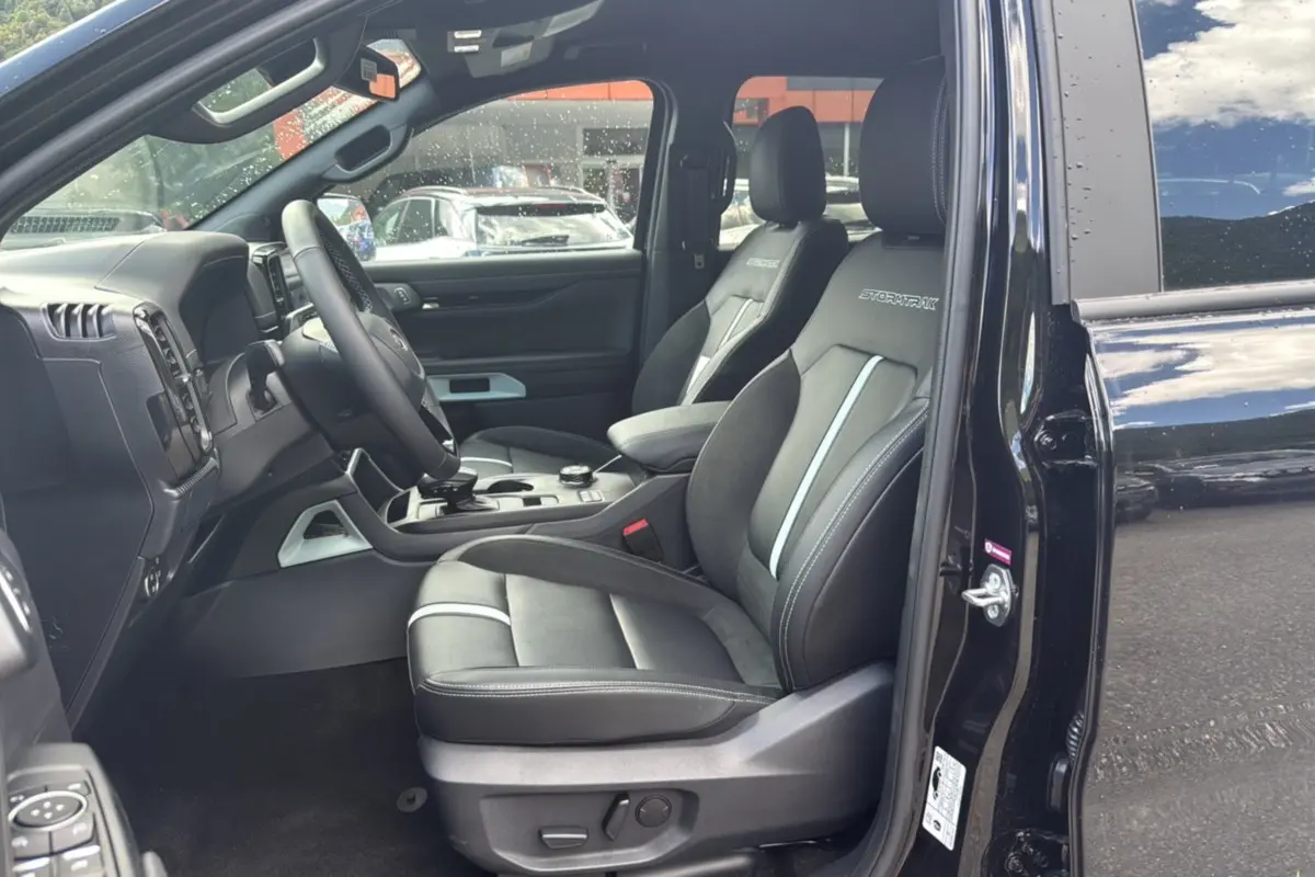 Vue intérieure côté conducteur du Ford Ranger noir agate 2025, sièges Stormtrak avec surpiqûres et volant cuir multifonctions.