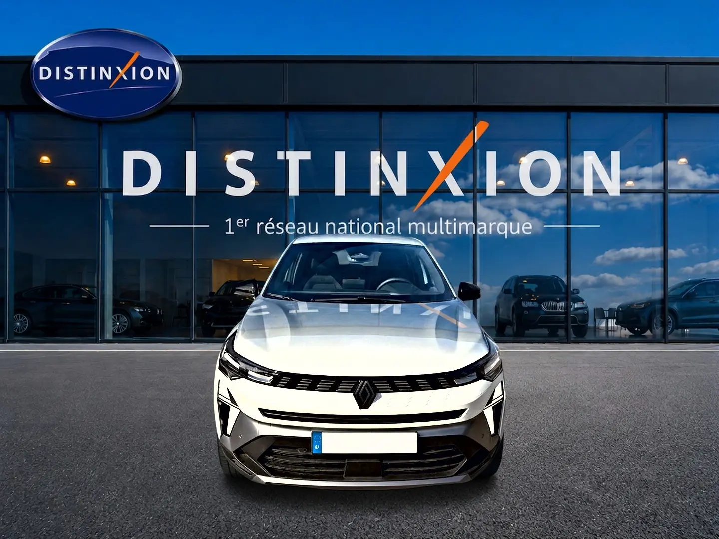 Vue frontale d'une Renault Symbioz blanc nacré, avec calandre noire et logo Renault bien visible, devant une vitrine Distinxion.