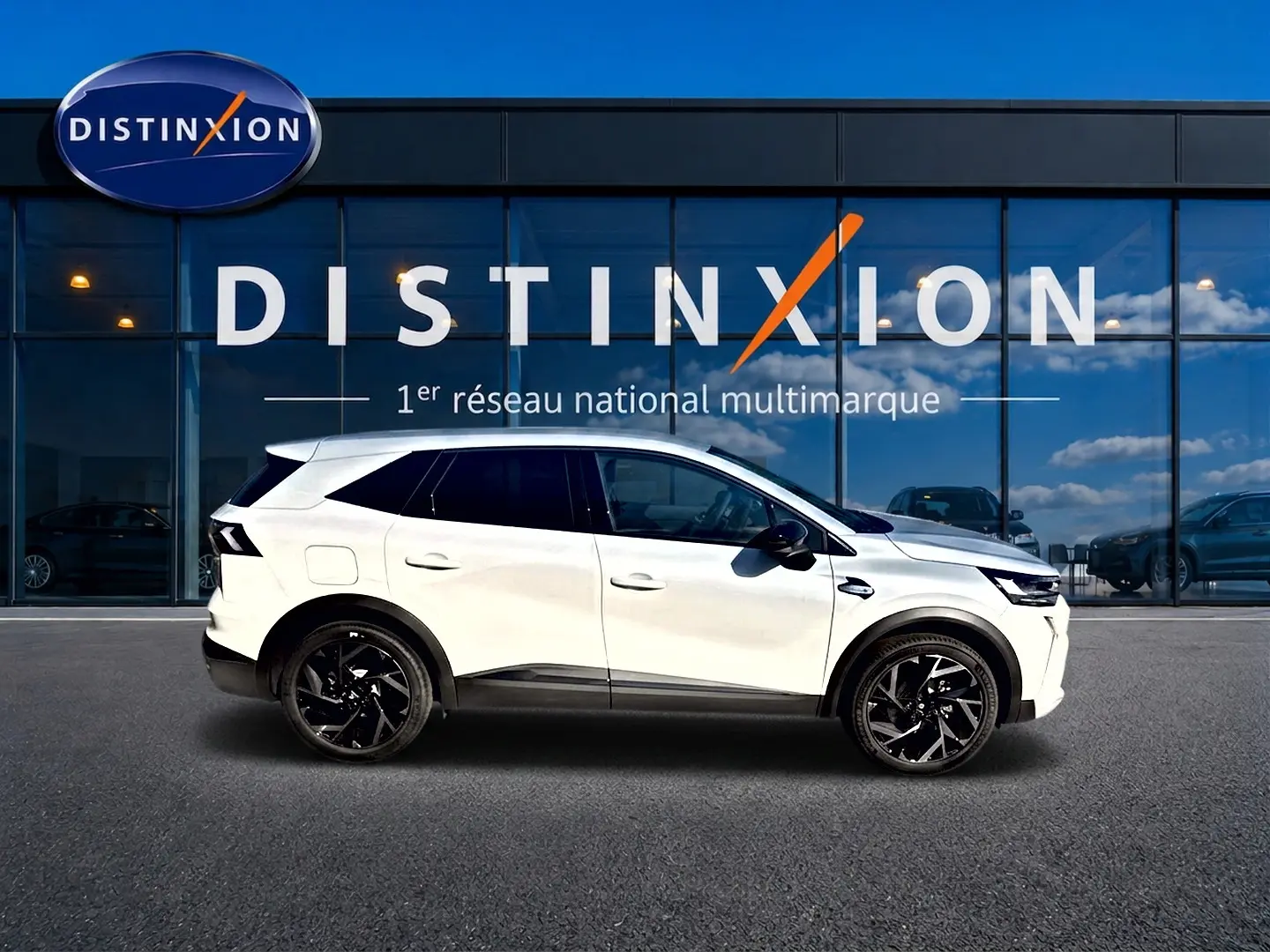 Profil droit du Renault Symbioz blanc nacré avec jantes noires, garé devant une vitrine Distinxion.