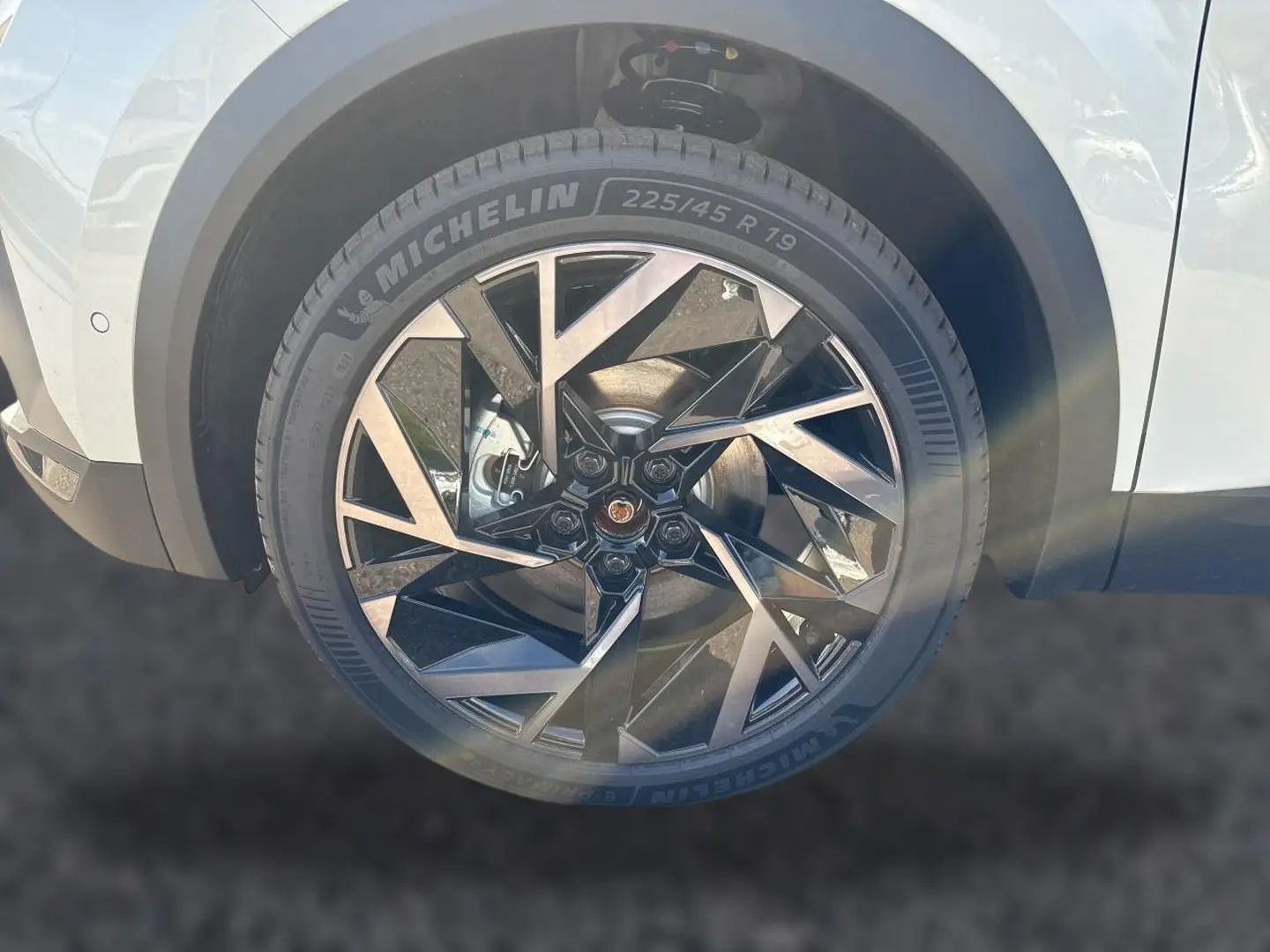 Gros plan sur la roue avant droite d’une Renault Symbioz blanc nacré avec jante alu noire et argentée au design géométrique.