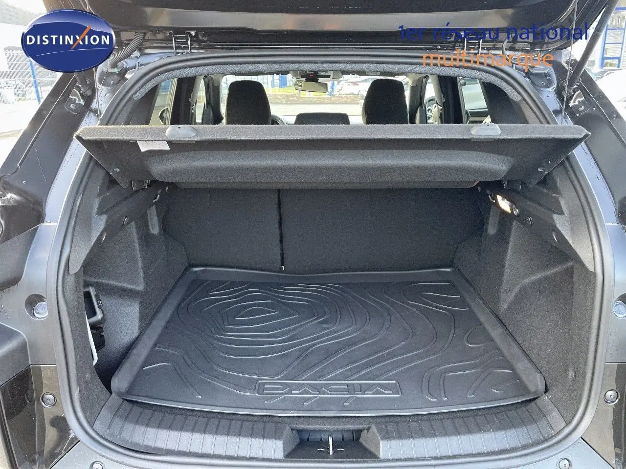 Coffre ouvert d'un Dacia Duster noir métal 2024, mettant en valeur le tapis de coffre avec logo DACIA.