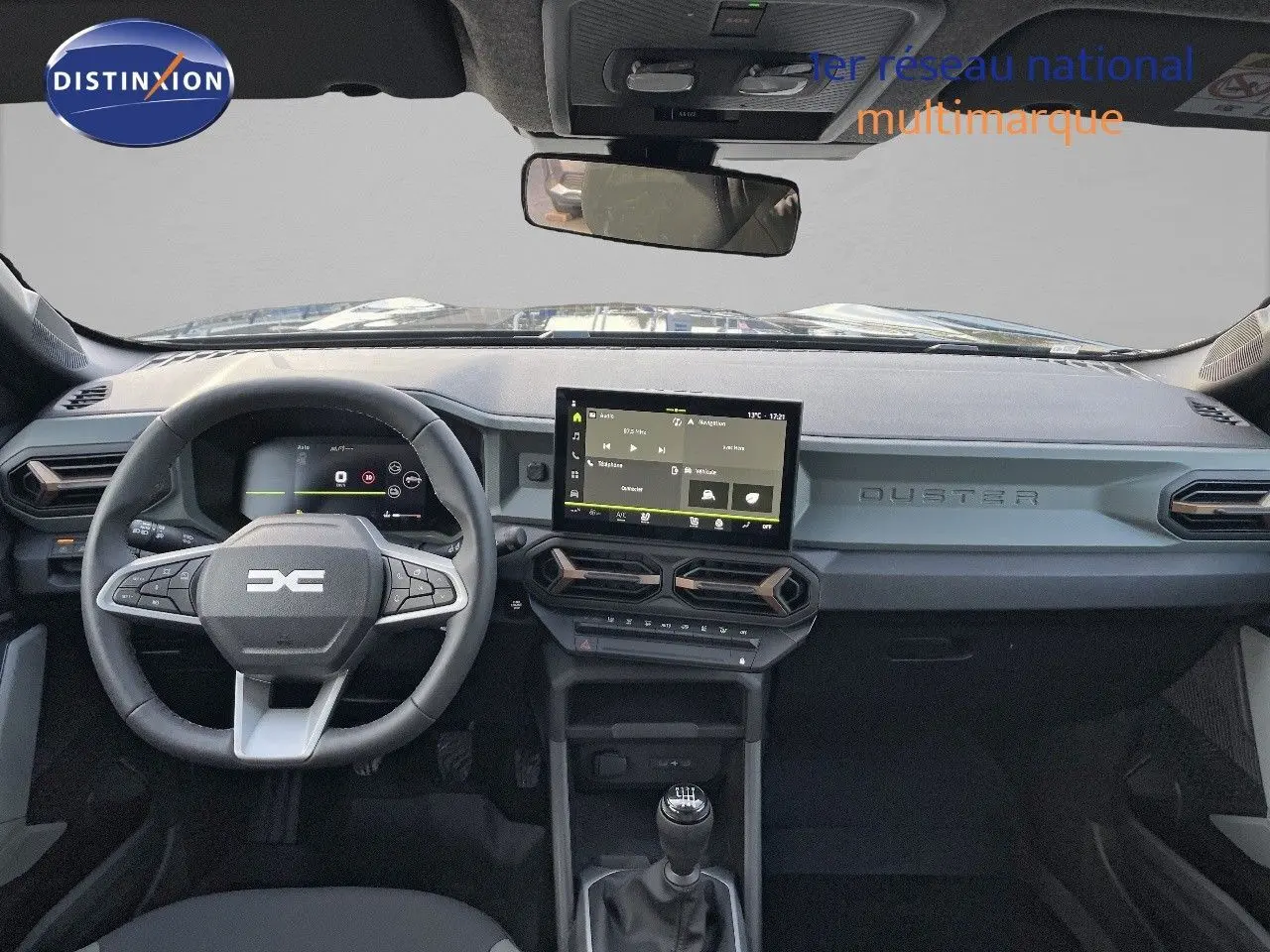 Tableau de bord noir du Dacia Duster 2024 avec volant multifonction, écran tactile et levier de vitesses manuel visible de face.