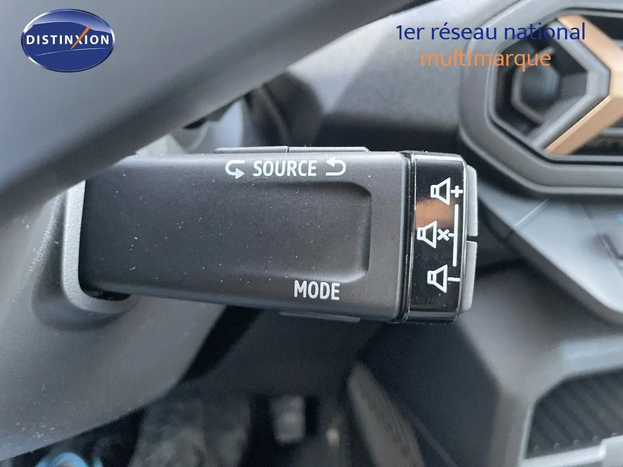 Gros plan sur la commande multimédia au volant du Dacia Duster noir métal 2024, avec détails des boutons source et mode.