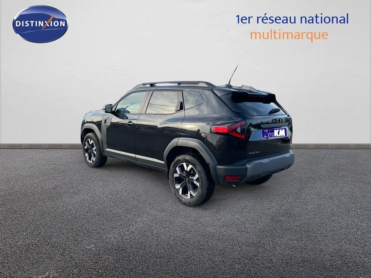 Vue 3/4 arrière d'un Dacia Duster noir métal 2024 avec jantes bi-ton et barres de toit sur fond neutre.