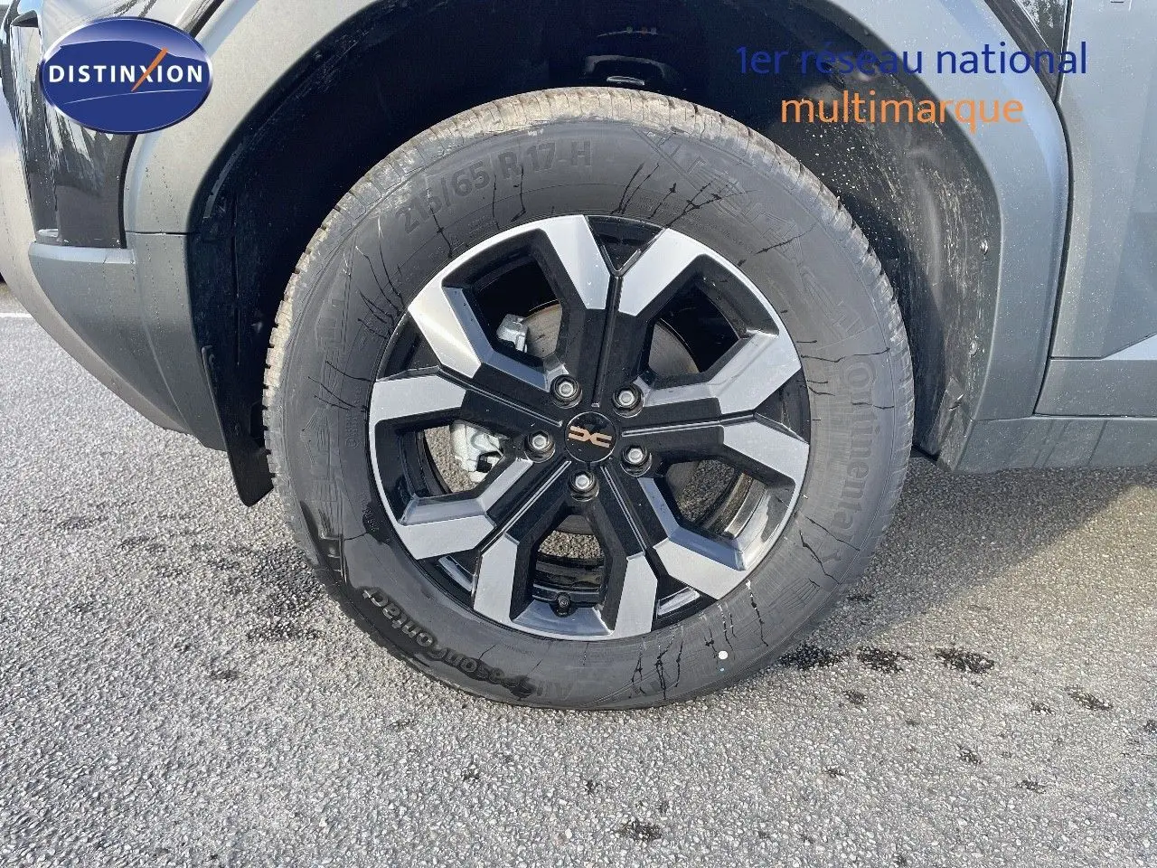 Gros plan sur la roue avant gauche du Dacia Duster noir métal 2024, mettant en valeur la jante bi-ton distinctive.