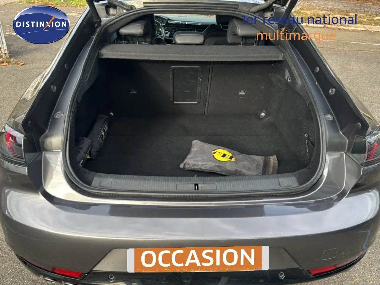 Vue arrière ouverte sur le coffre spacieux d'une Peugeot 508 gris platinium, avec attelage visible et intérieur noir.