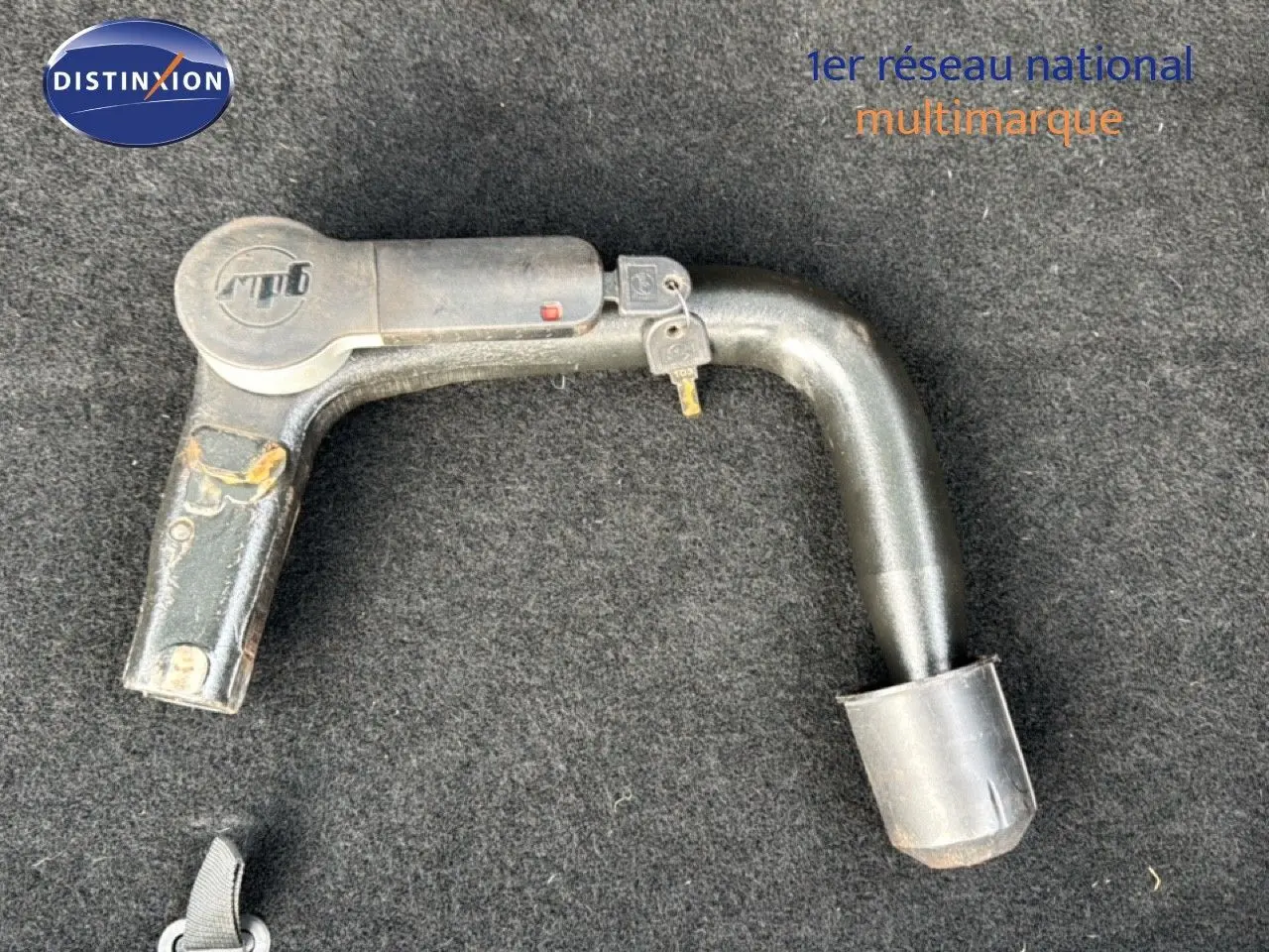 Gros plan sur l'attelage noir amovible posé sur un tapis gris, accessoire distinctif du Peugeot 508 gris platinium.