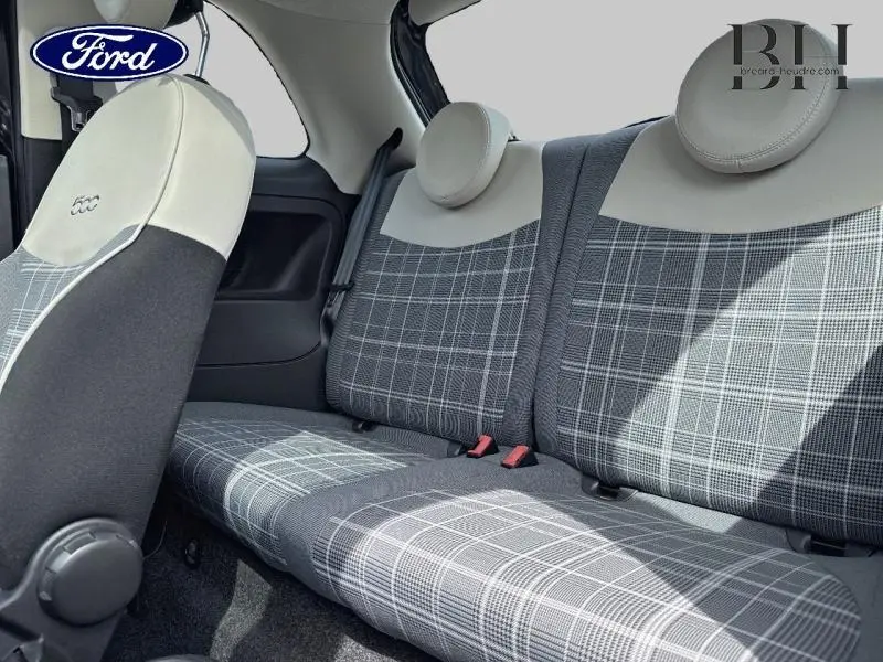 Vue intérieure sur la banquette arrière à motifs carreaux gris et appuie-têtes ronds clairs d'une Fiat 500 noire.