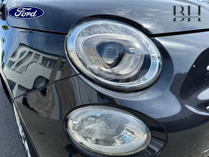 Gros plan sur le phare avant droit d'une FIAT 500 Lounge 2018 en Crossover Black Métal avec reflets brillants.