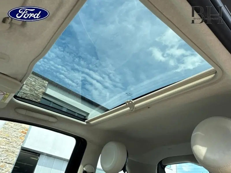Vue intérieure du toit panoramique en verre du Fiat 500 Crossover Black Métal, avec ciel visible à travers la vitre ouverte.