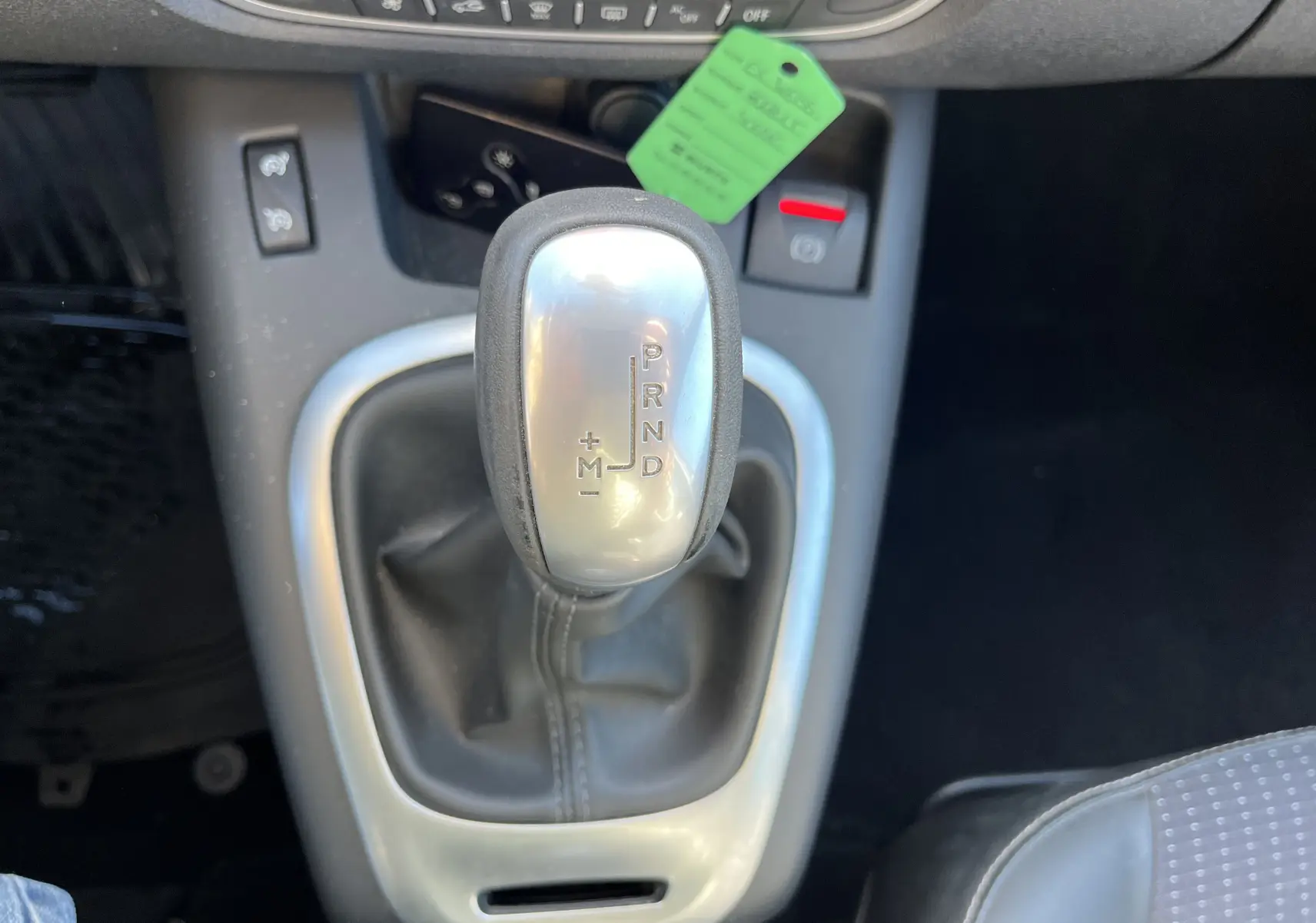 Gros plan sur le levier de vitesses automatique argenté du Renault Scenic III noir, avec console centrale et siège tissu visible.