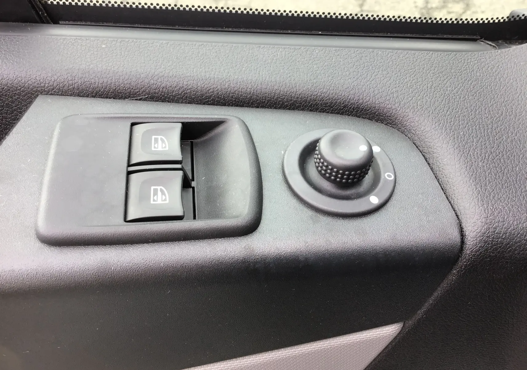 Gros plan sur les commandes de lève-vitres et réglage des rétroviseurs côté conducteur du Renault Trafic Planche Cabine blanc 2019.