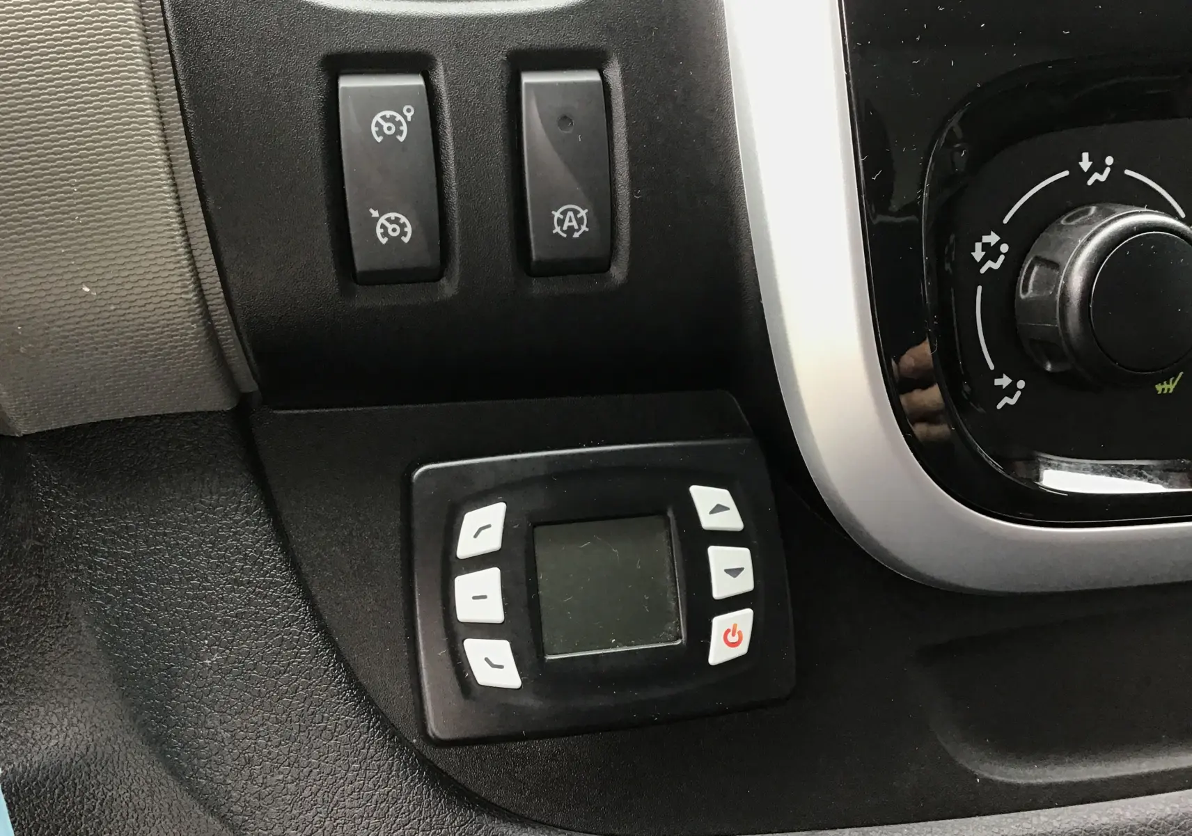 Gros plan sur le tableau de bord noir du Renault Trafic blanc, montrant les commandes du régulateur et du groupe frigorifique.