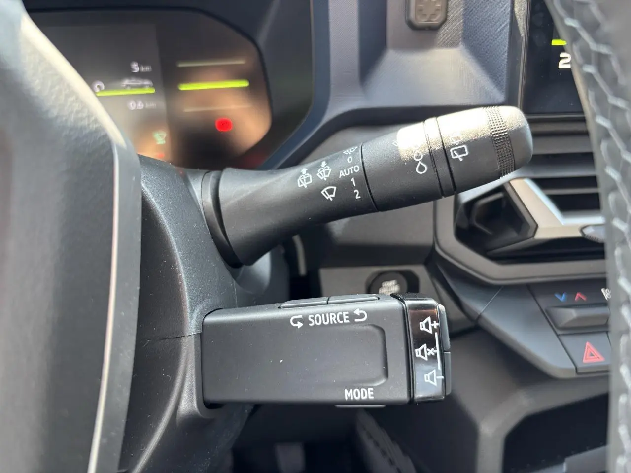 Gros plan sur les commandes au volant du Dacia Duster 2025, avec tableau de bord digital en arrière-plan.