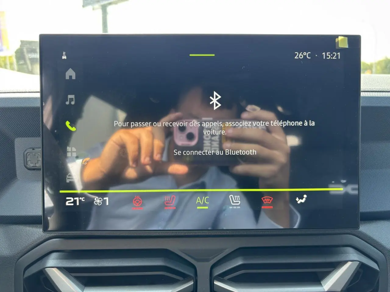 Écran tactile central du tableau de bord du Dacia Duster III vert cèdre, affichant la connexion Bluetooth et commandes climatisation.
