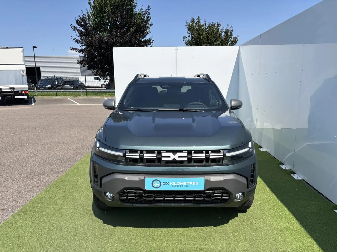 Vue de face du Dacia Duster 2025 en vert cèdre métallisé avec calandre moderne et feux LED fins.