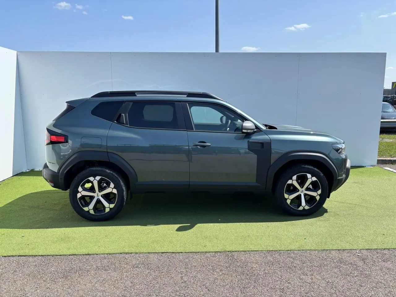 Profil côté gauche du SUV Dacia Duster 2025 en Vert Cèdre Métal avec jantes alliage 18 pouces diamantées.