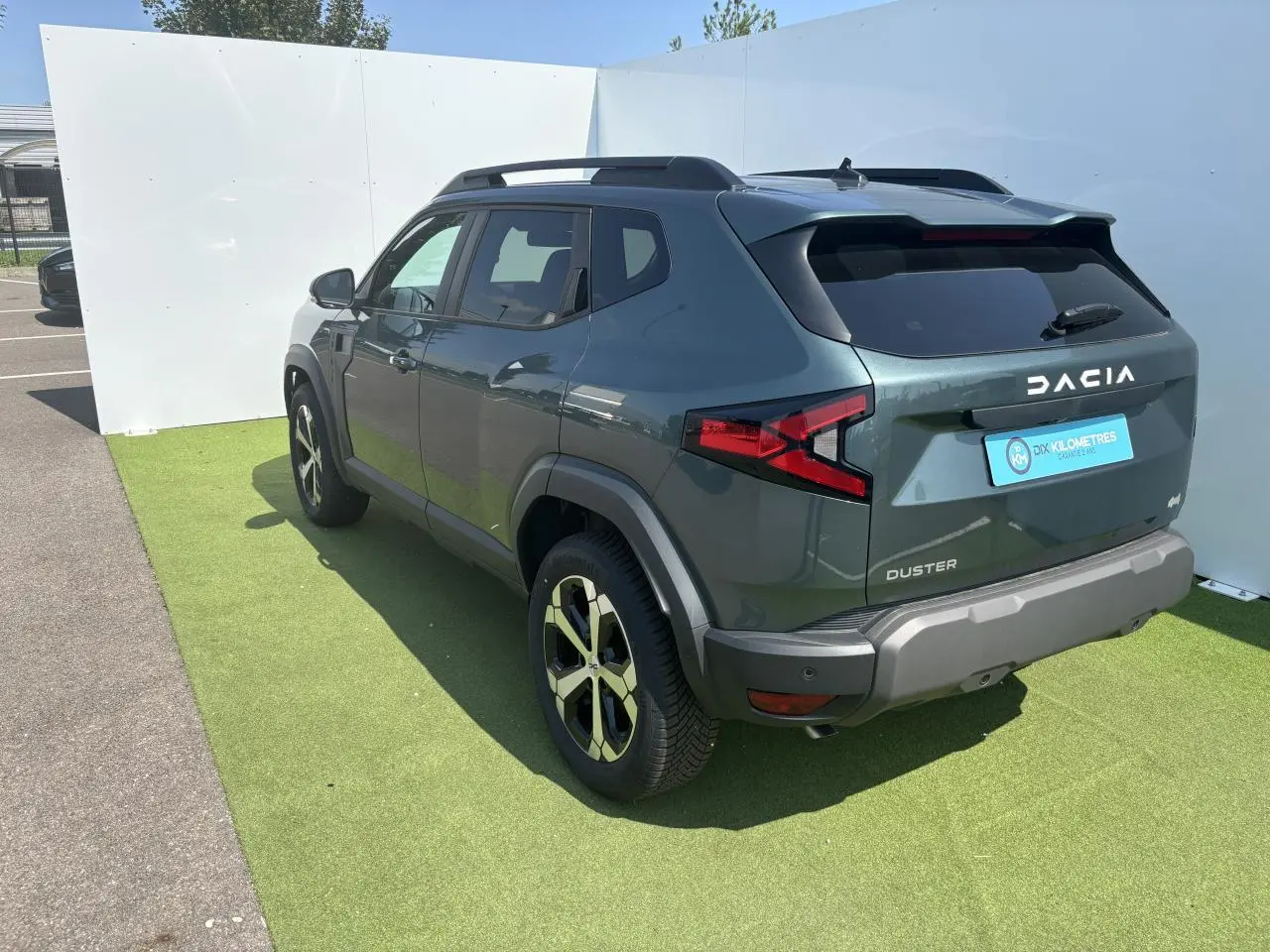 Vue 3/4 arrière droite du Dacia Duster 2025 en Vert Cèdre Métal avec jantes alliage 18 pouces diamantées.