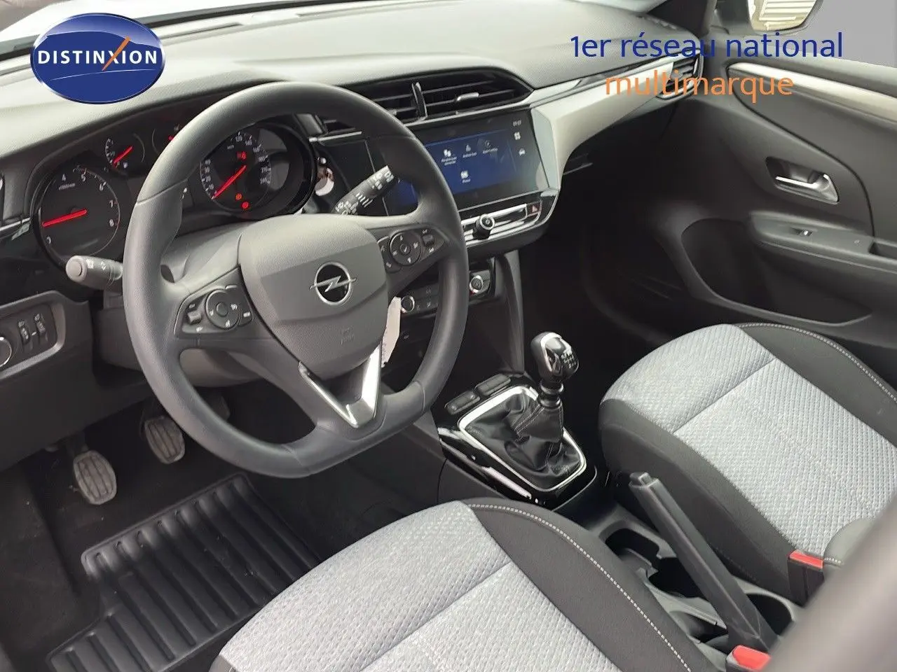 Vue intérieure avant droite de l'Opel Corsa 2025, montrant le volant multifonction, la boîte manuelle et les sièges gris clair.