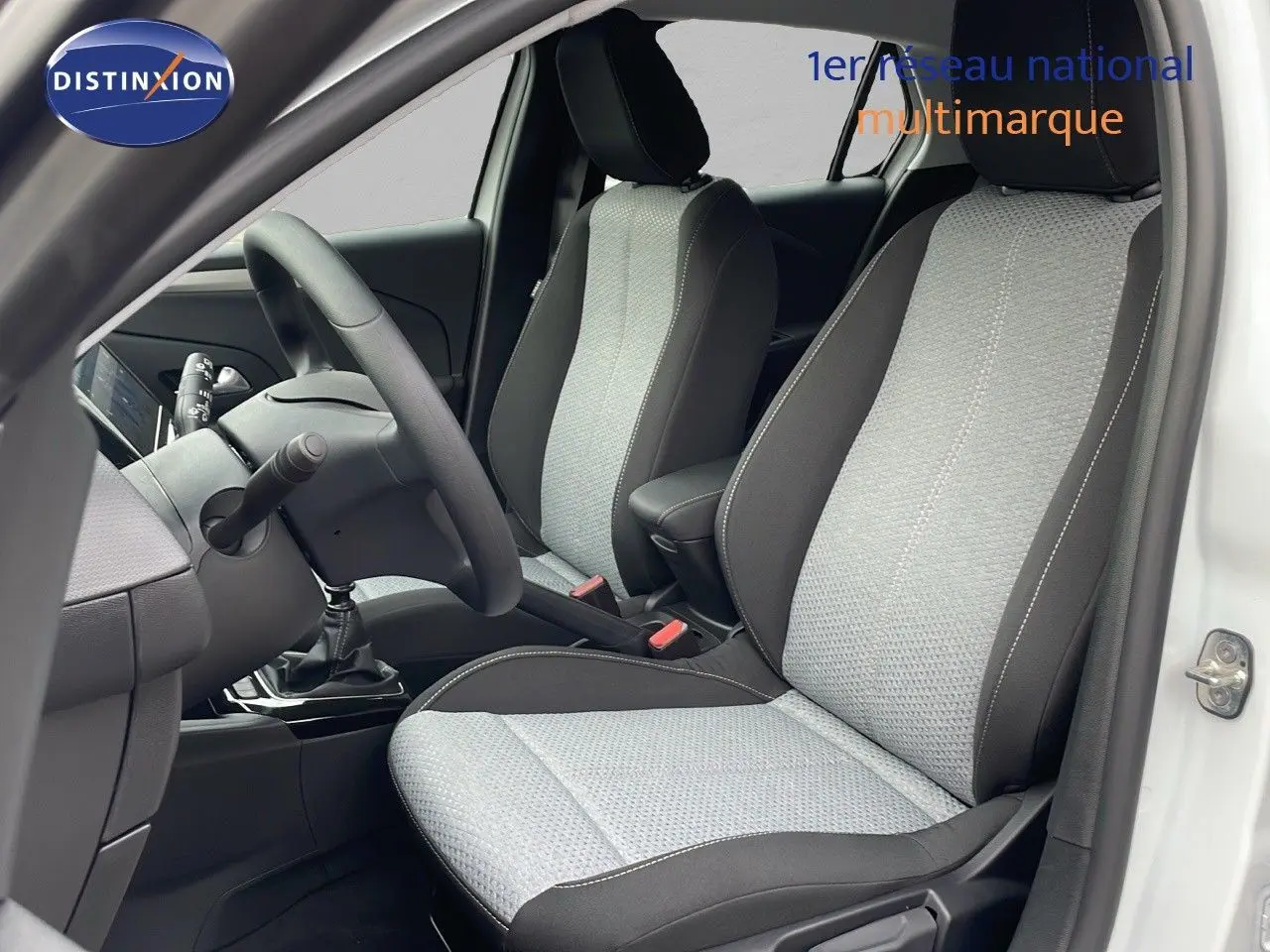 Vue intérieure côté conducteur de l'Opel Corsa blanc arctique 2025 avec sièges tissu bicolore gris et noir.