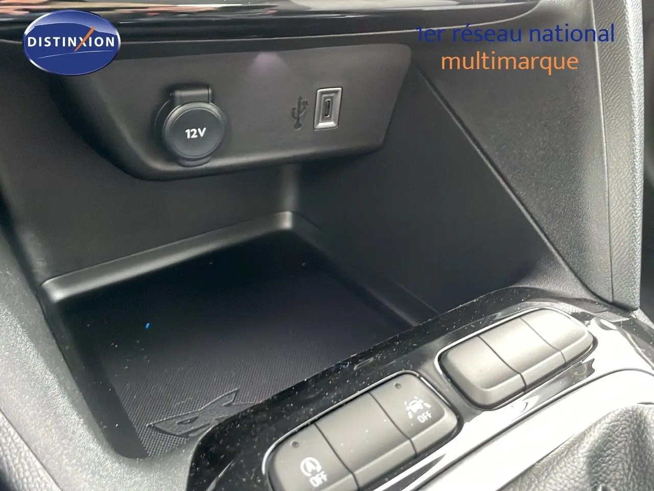 Gros plan sur la console centrale de l'Opel Corsa blanc arctique, montrant prise 12V, port USB et boutons de commande.