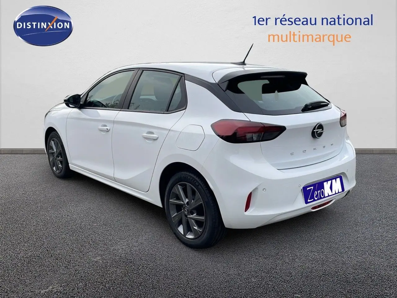 Opel Corsa blanc arctique vue 3/4 arrière droit, avec jantes gris foncé et feux arrière LED foncés.