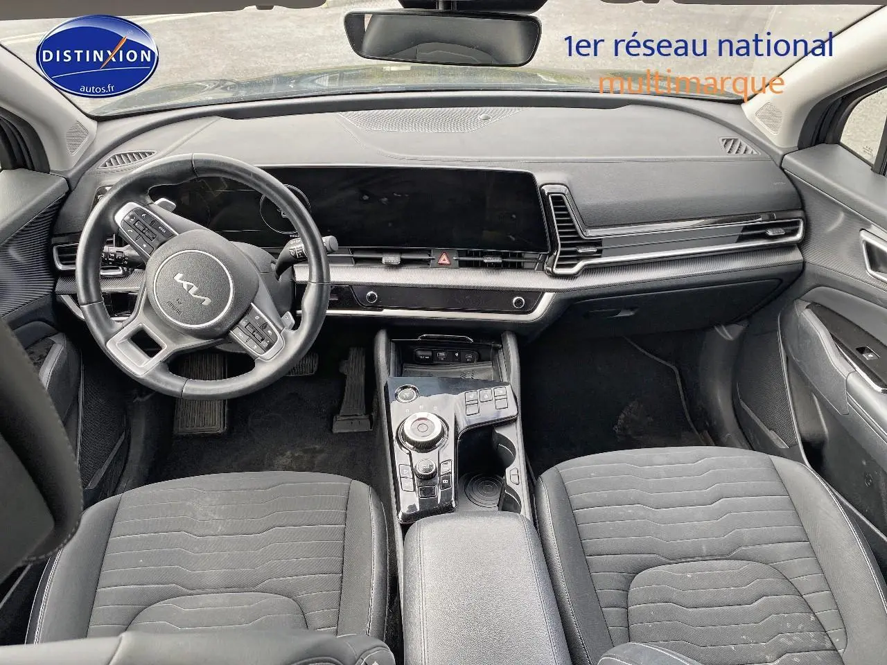 Intérieur noir du Kia Sportage 2023 vu de face, avec volant cuir multifonction et large écran tactile.