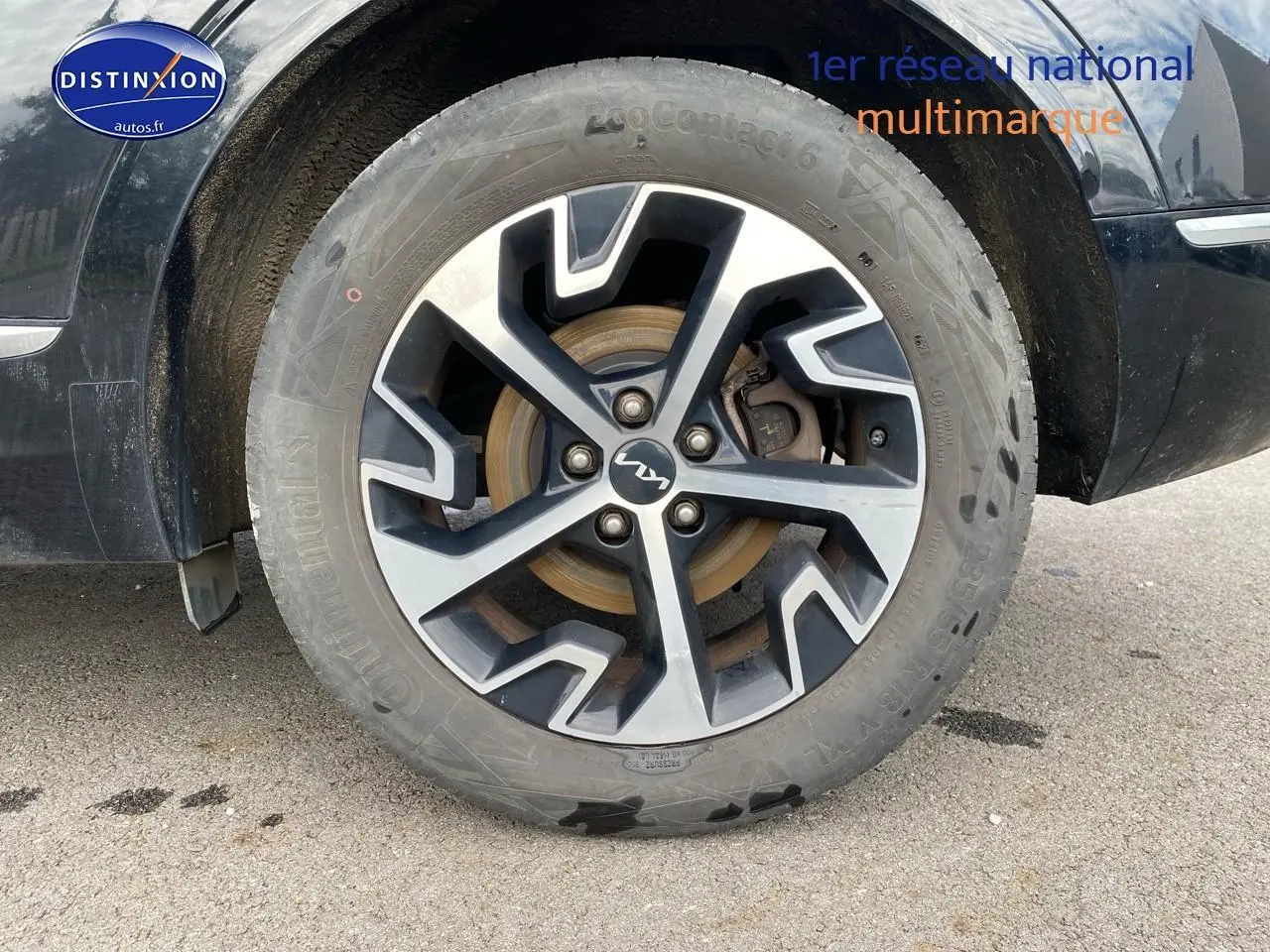 Gros plan sur la roue avant droite du Kia Sportage noir 2023 avec jante alu au design moderne.