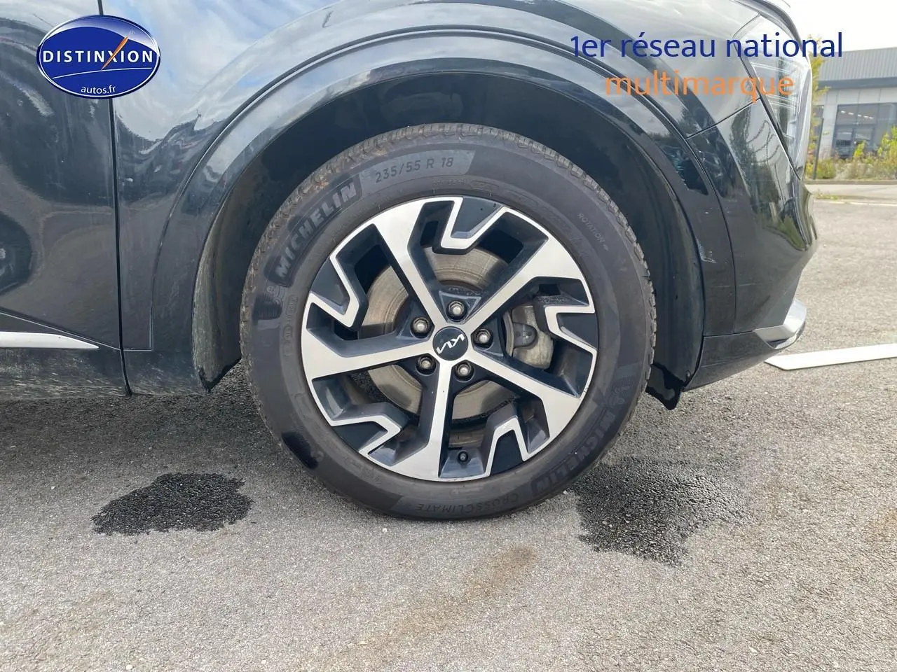 Gros plan sur la roue avant gauche du KIA SPORTAGE noir 2023 avec jante alu au design moderne.