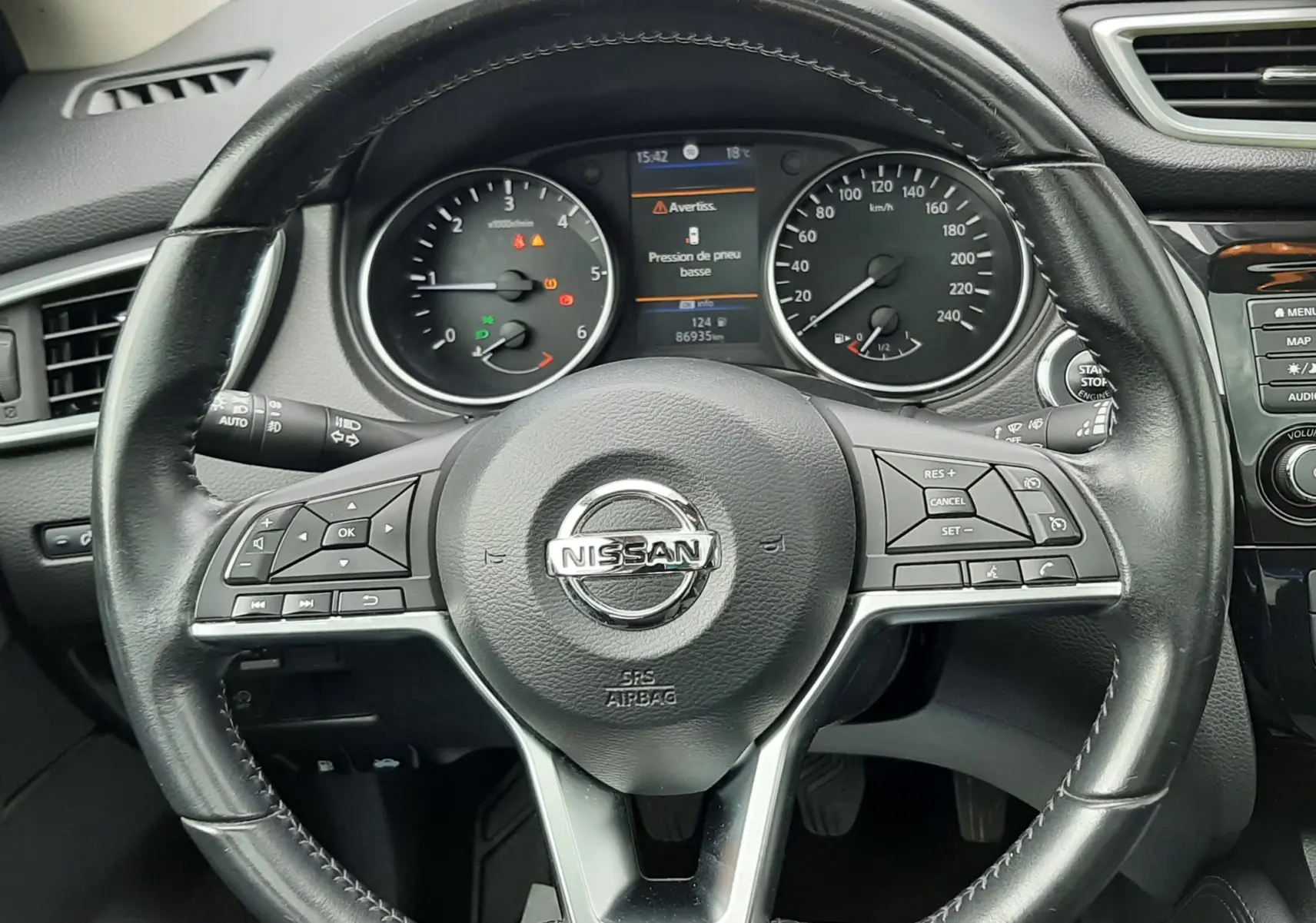 Vue rapprochée du volant en cuir noir d'un Nissan Qashqai 2020, avec tableau de bord et affichage digital au centre.