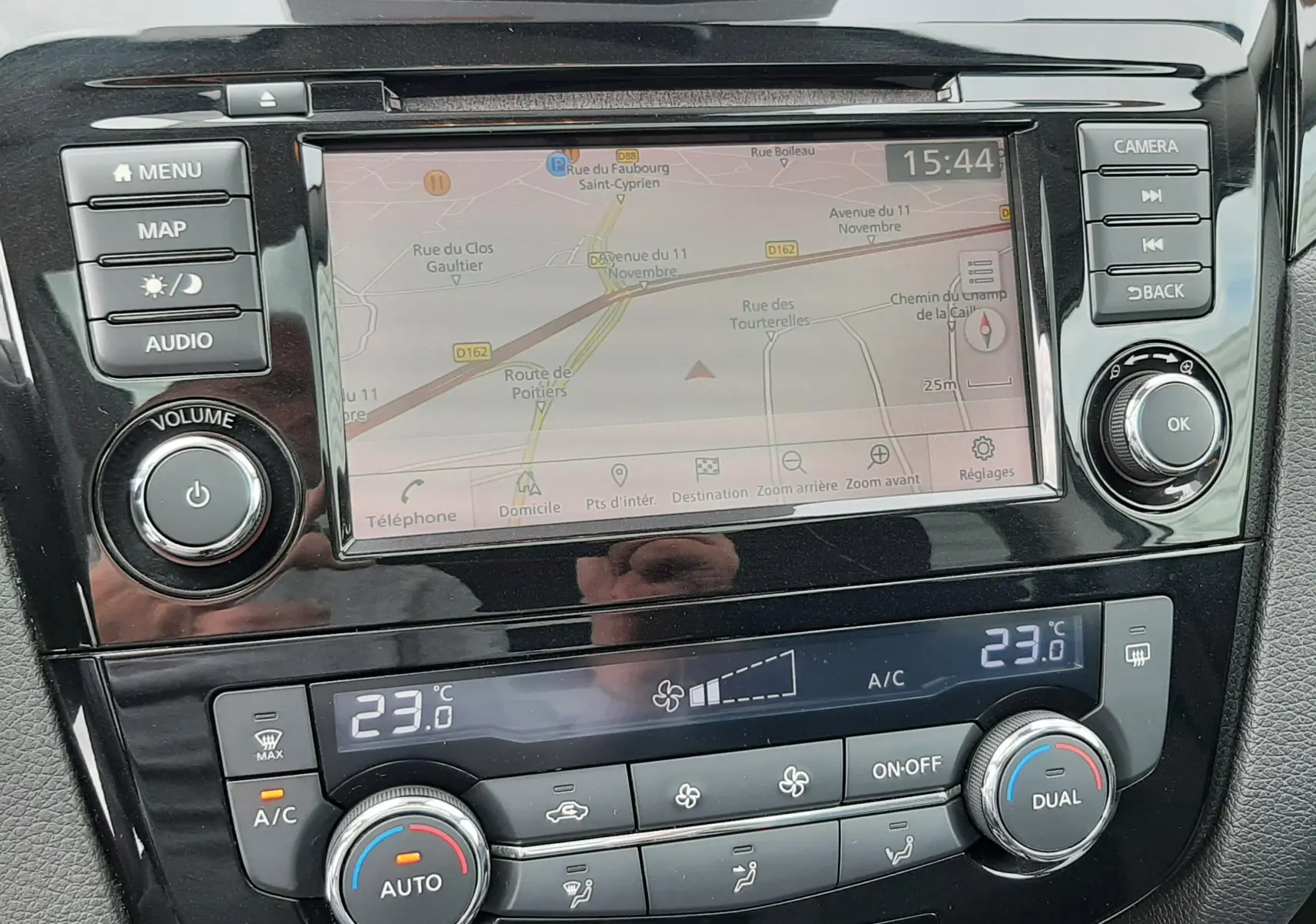 Vue rapprochée de la console centrale du Nissan Qashqai blanc 2020, affichant l'écran GPS et les commandes climatisation.