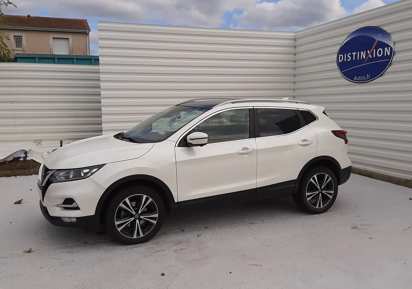 Nissan Qashqai blanc en vue de profil côté gauche, avec jantes alliage bicolores et vitres teintées.
