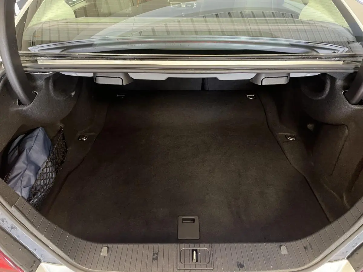 Coffre ouvert vu de l'arrière d'une Mercedes Classe CLS 350 d gris, avec filet de rangement latéral.