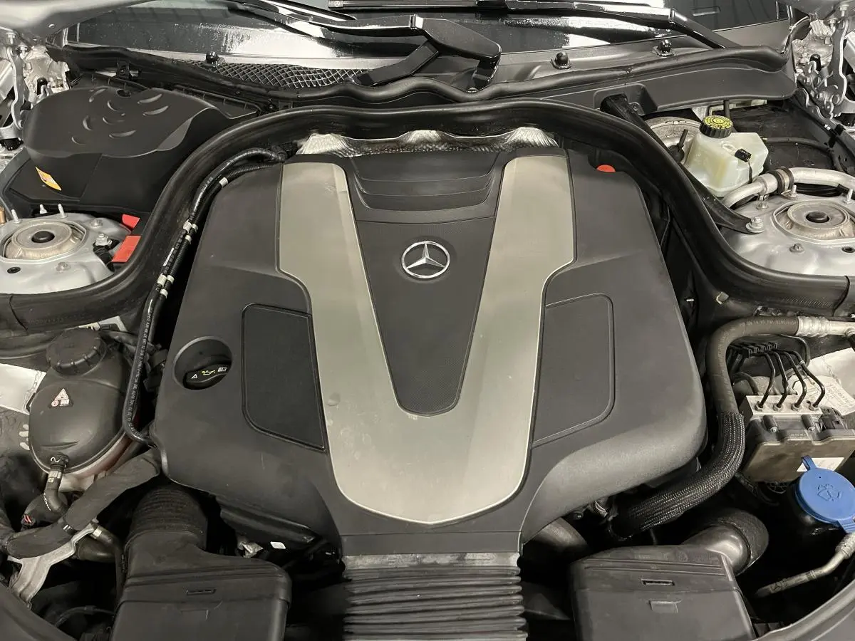 Vue rapprochée du moteur Mercedes Classe CLS 350 d 2015 avec cache noir et argenté sous le capot ouvert.