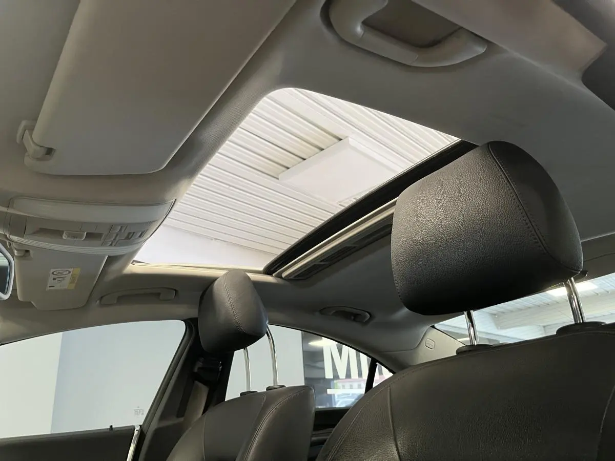 Vue intérieure montrant les appuie-têtes en cuir noir et le toit ouvrant vitré électrique d'une Mercedes CLS 350 d gris.