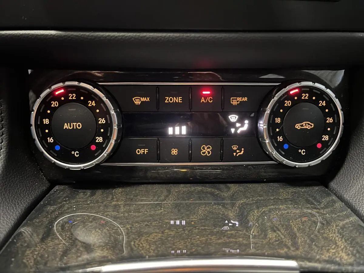 Panneau de climatisation automatique bi-zone avec réglages numériques et finition bois sombre dans une Mercedes CLS 350 d gris.