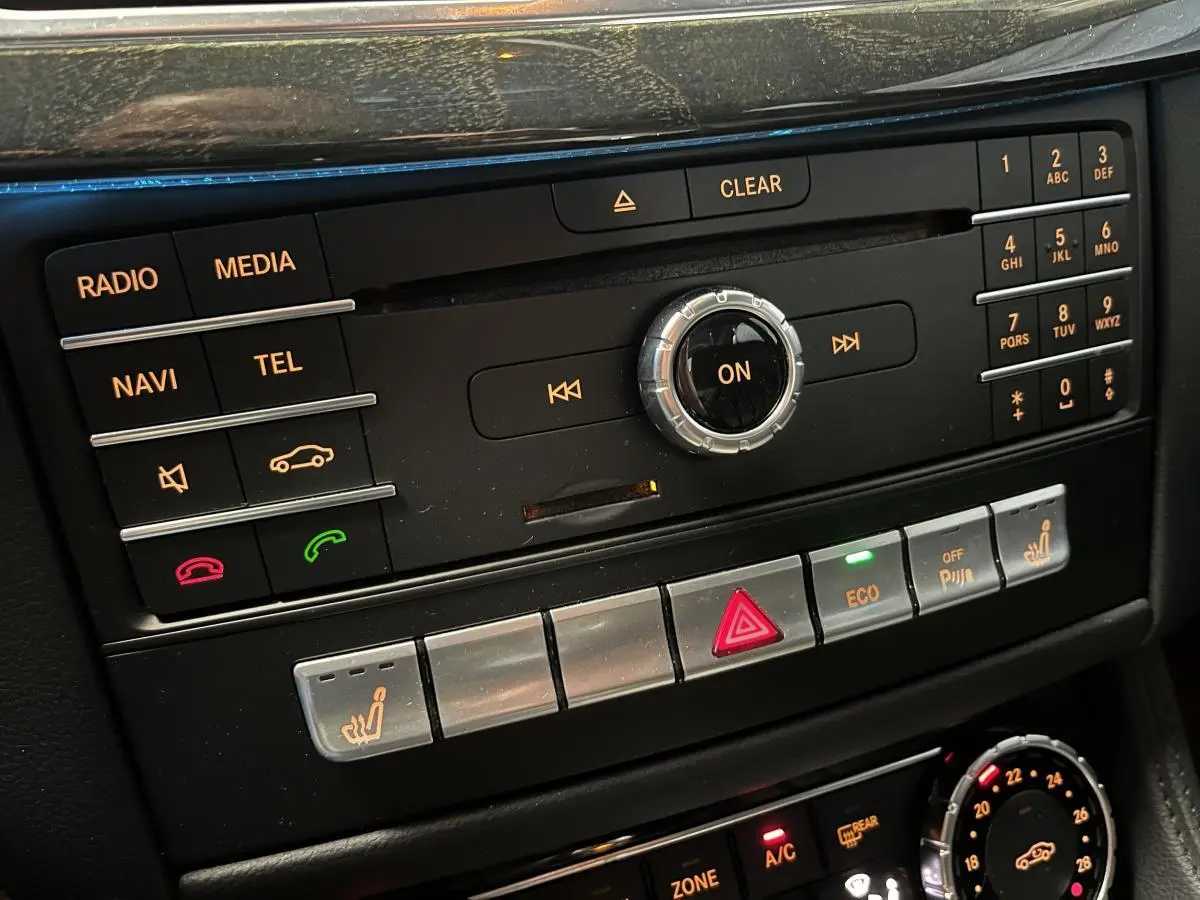 Console centrale de la Mercedes Classe CLS 350 d 2015 montrant les commandes multimédia et climatisation avec boutons rétroéclairés.