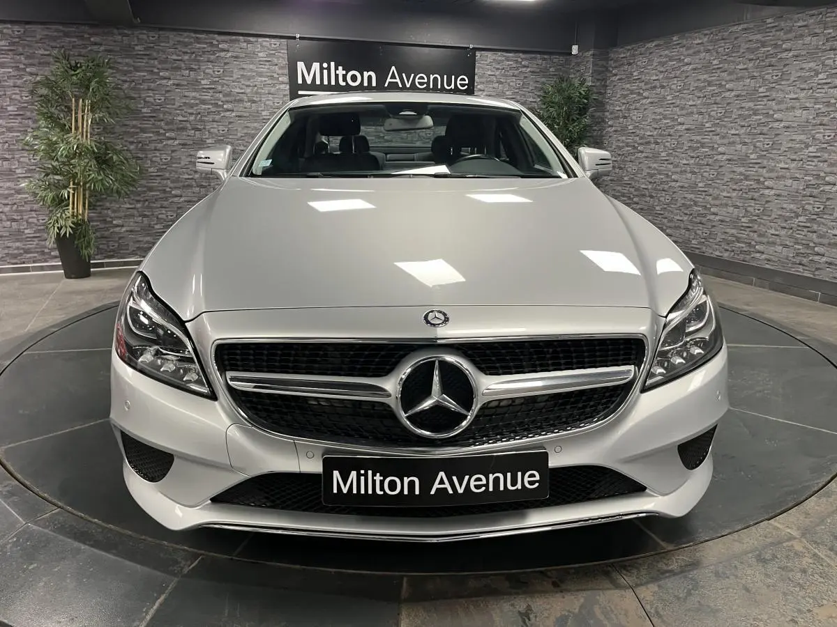 Vue frontale d'une Mercedes Classe CLS 350 d gris métallisé avec calandre chromée et logo central sur fond noir.