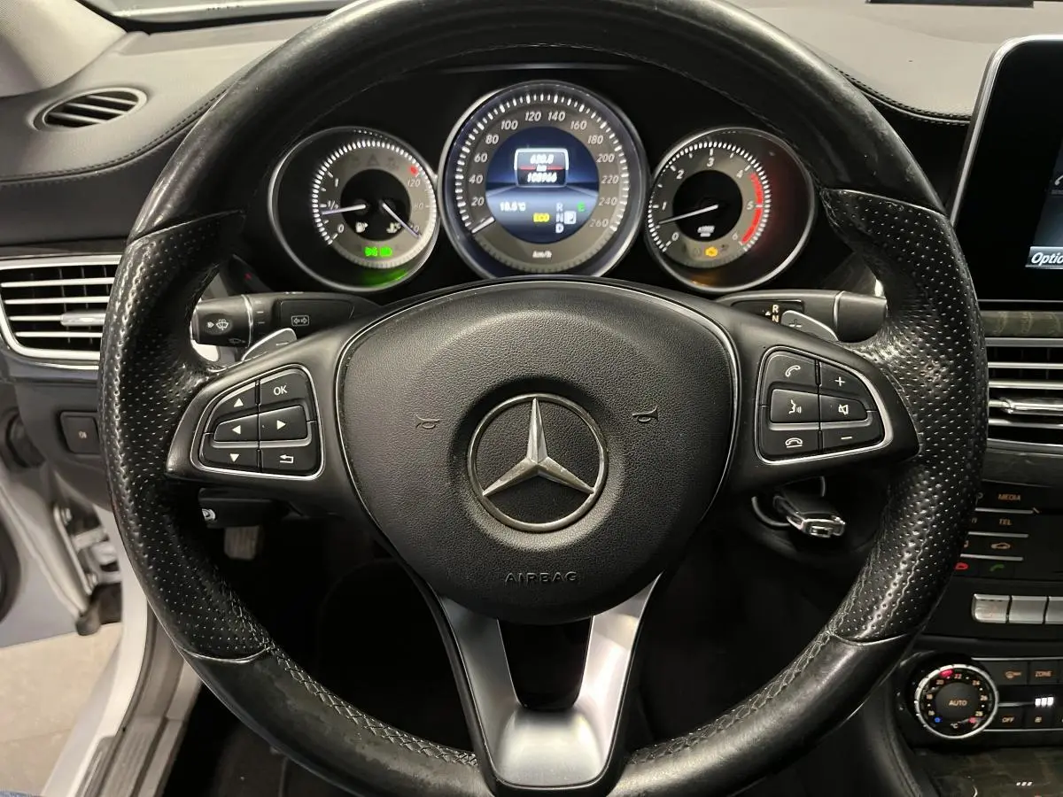 Vue rapprochée du volant cuir noir perforé et du tableau de bord digital d'une Mercedes CLS 350 d gris de 2015.