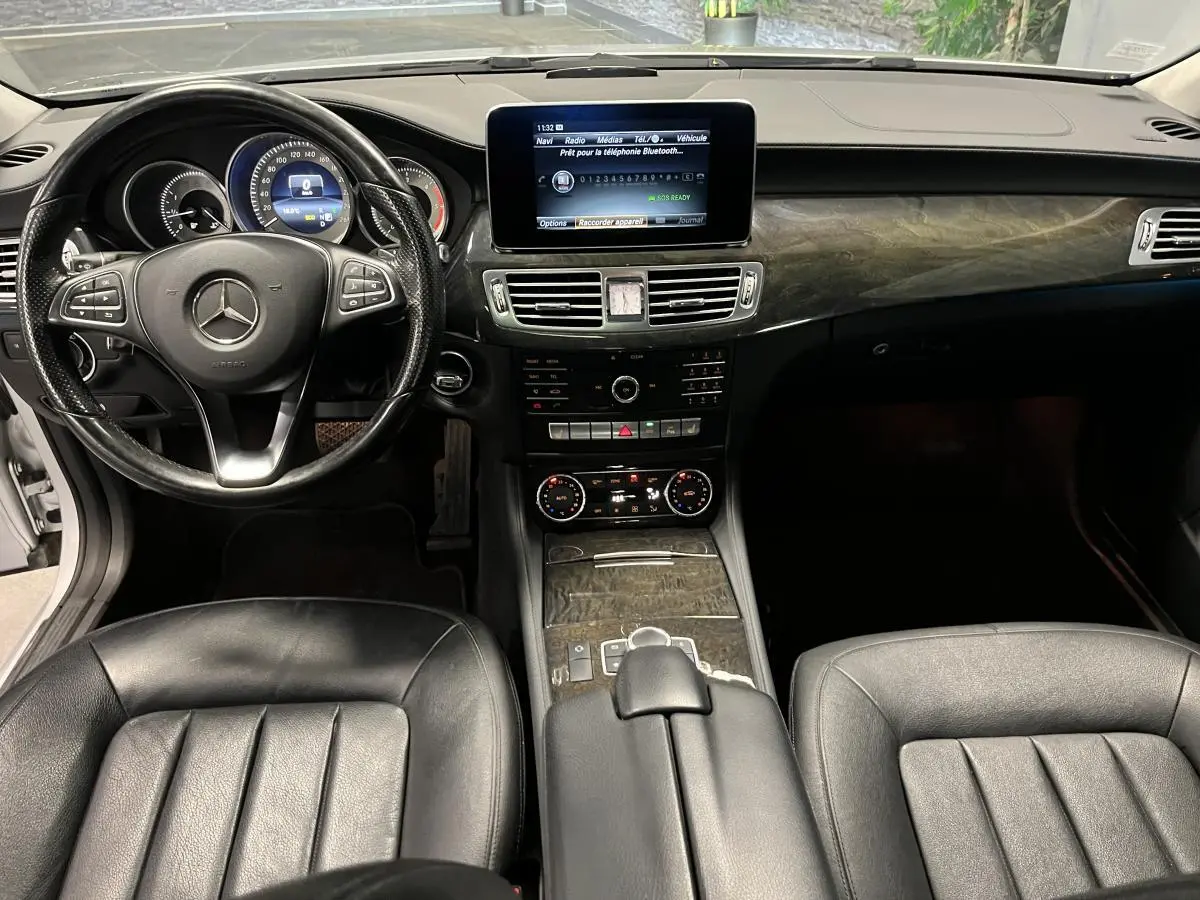 Intérieur noir cuir de la Mercedes CLS 350 d 2015, tableau de bord avec écran central et inserts bois foncé.