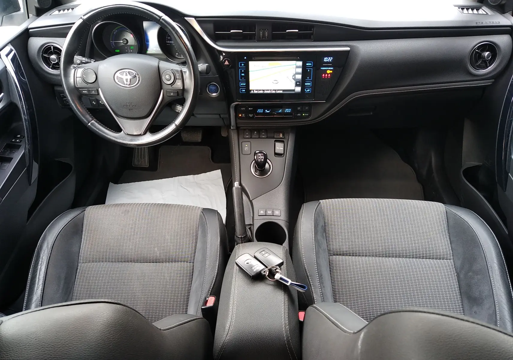 Vue intérieure avant de la Toyota Auris hybride 2016, avec tableau de bord noir et clés posées sur l'accoudoir central.