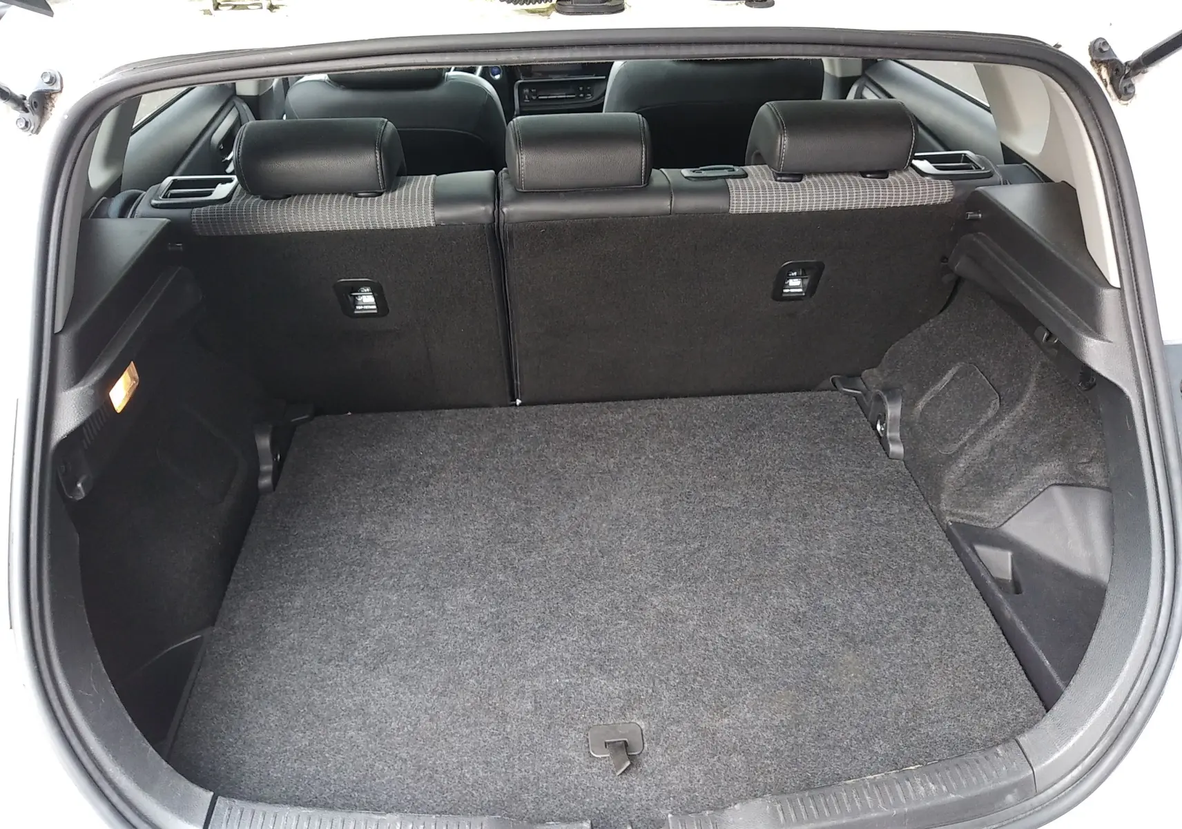 Coffre ouvert d'une Toyota Auris blanche, vue arrière montrant l'espace de chargement et les dossiers de sièges noirs.