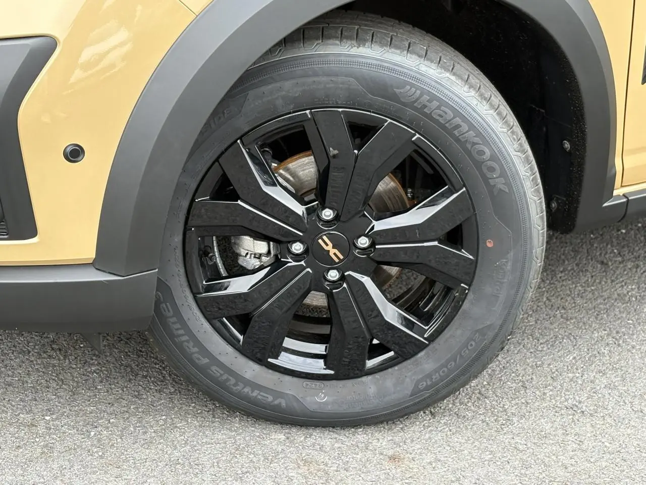 Gros plan sur la roue avant droite noire brillante de la Dacia Sandero Stepway Beige Safari avec jante alu 16 pouces.