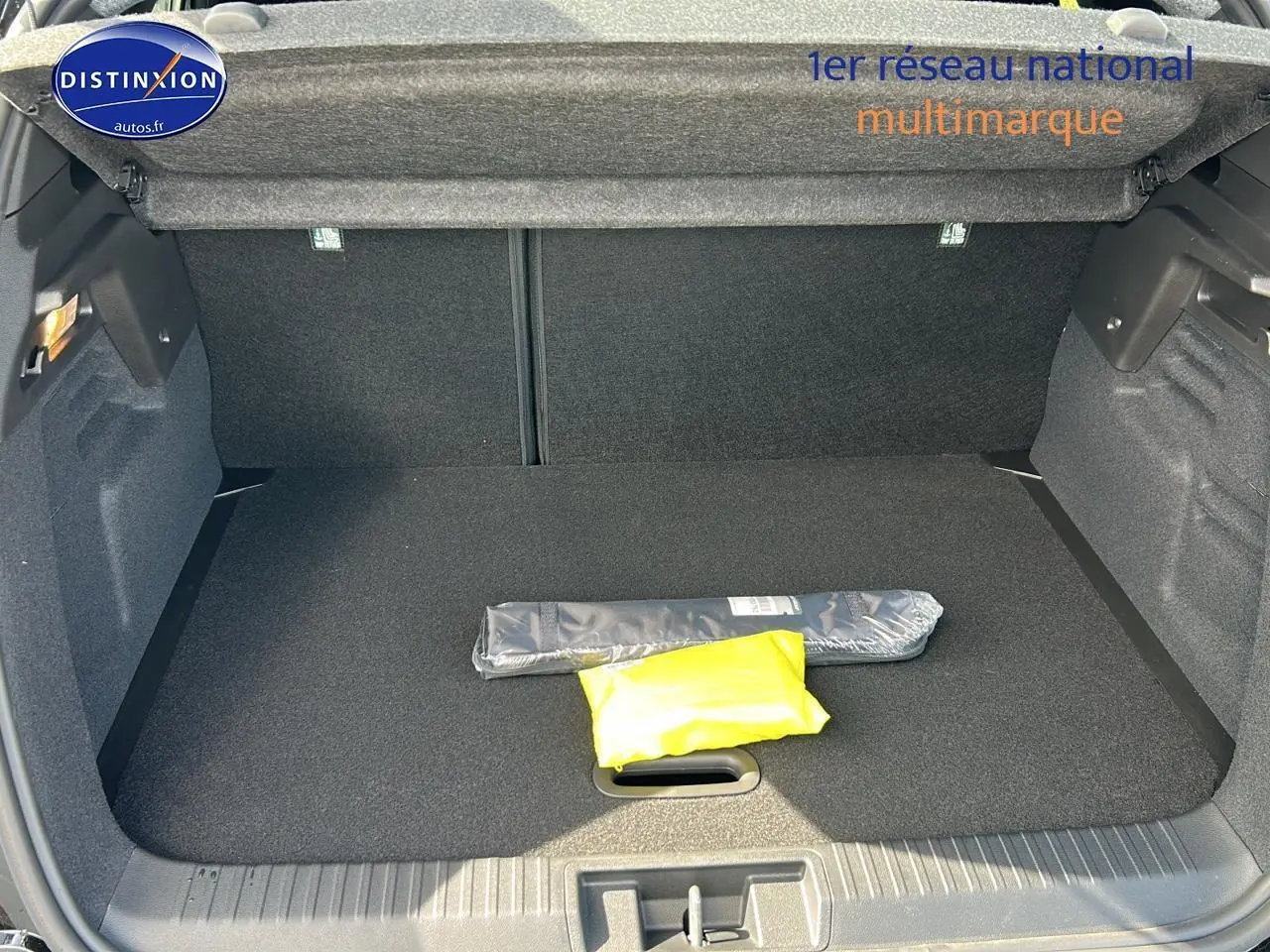 Coffre ouvert vu de l'arrière du Renault Captur noir Étoile, montrant un tapis noir et deux objets emballés.