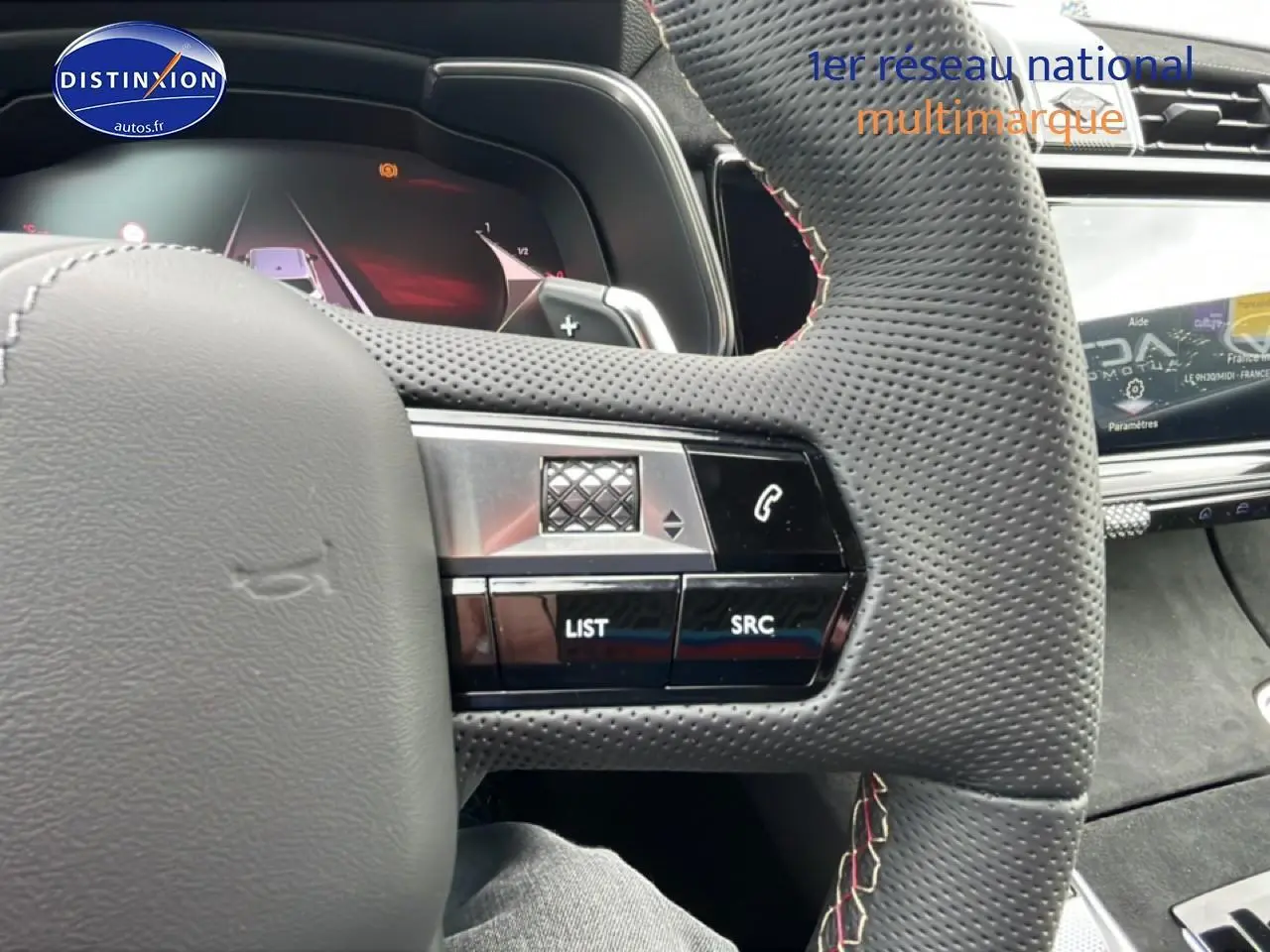 Gros plan sur le volant cuir perforé noir du DS7 1.5 BlueHDi 130 avec commandes au volant et écran tactile en arrière-plan.